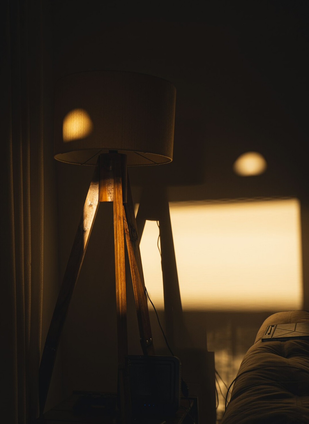 Person reading a book by warm lamp light surrounded by stacks of books