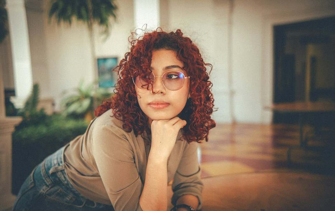 Studio portrait of a young Latina woman writer with curly hair, neutral background