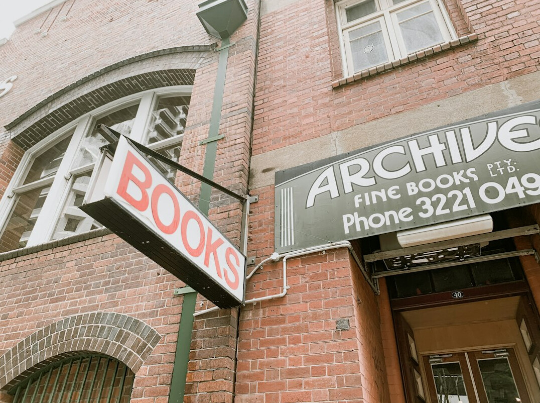 Tall wooden shelves filled with old books in a dim archive library